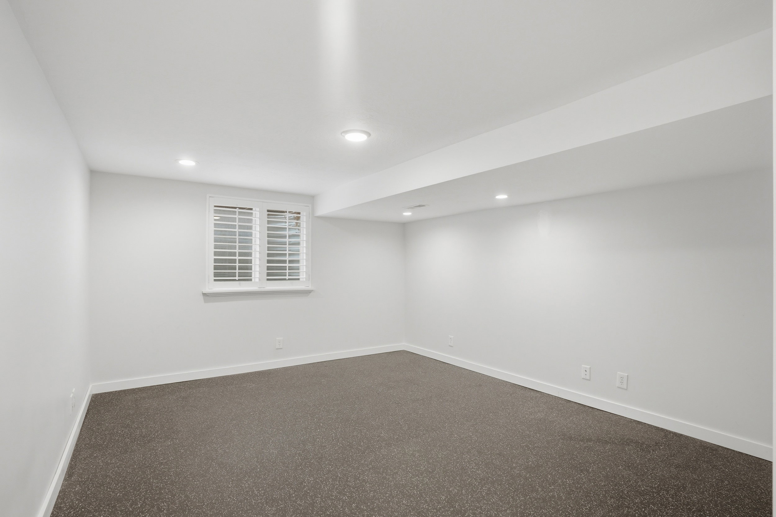 Finished basement exercise room with dark flooring and recessed lighting