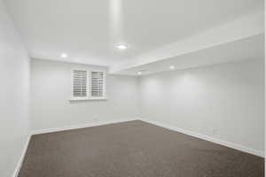 Finished basement exercise room with dark flooring and recessed lighting