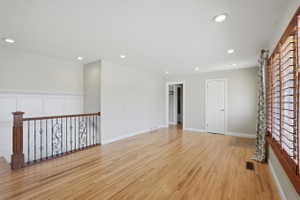 Spacious interior featuring wood-finish flooring, recessed lighting, and a decorative wrought iron railing with a wood-stained top rail and newel post