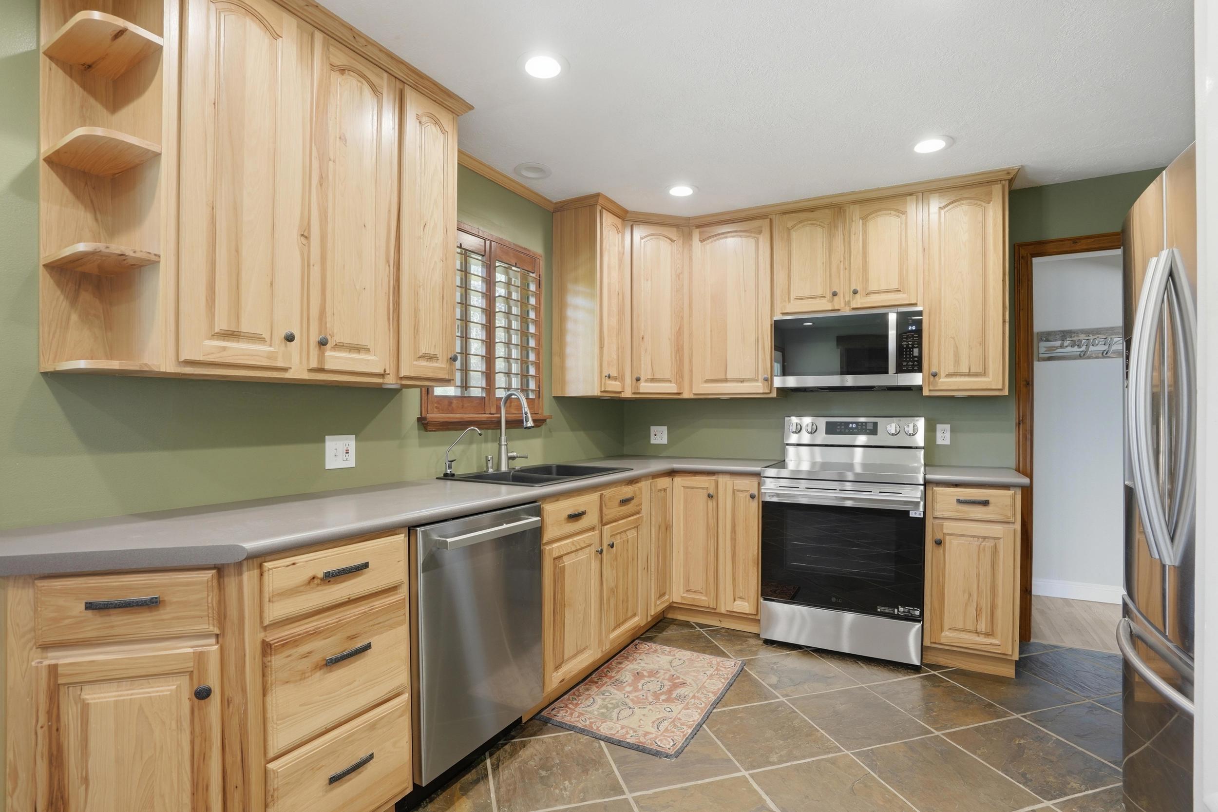 Kitchen featuring abundant wood cabinetry, stainless steel appliances, a built-in microwave, and tile flooring