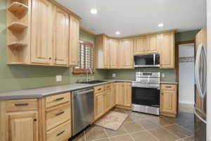 Kitchen featuring abundant wood cabinetry, stainless steel appliances, a built-in microwave, and tile flooring