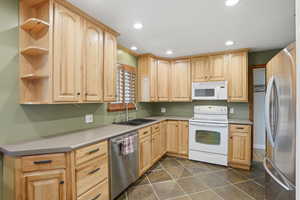 Kitchen with light wood finish cabinets, stainless steel appliances, open shelves, recessed lighting, and light countertops