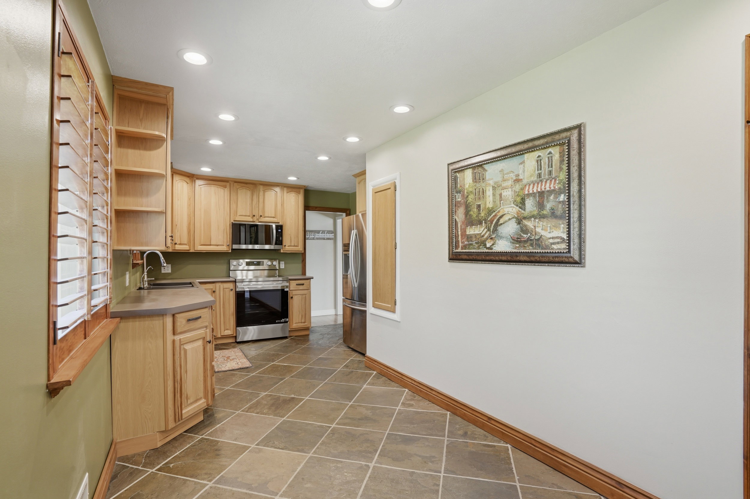 Kitchen featuring light wood cabinetry, stainless steel appliances, recessed lighting, and a tile floor