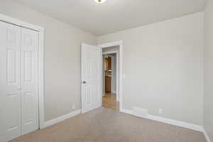 Unfurnished bedroom with light colored carpet and a closet