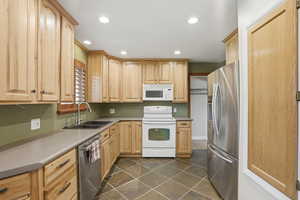 Kitchen featuring stainless steel appliances, light wood finish cabinets, recessed lighting, and light countertops