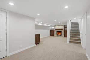 Finished basement featuring recessed lighting, light carpet, and a large fireplace