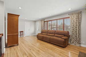 Living area with light wood-type flooring and recessed lighting