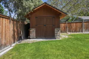 Wood-sided storage shed featuring stone veneer accents, double doors, and an overhanging roofline