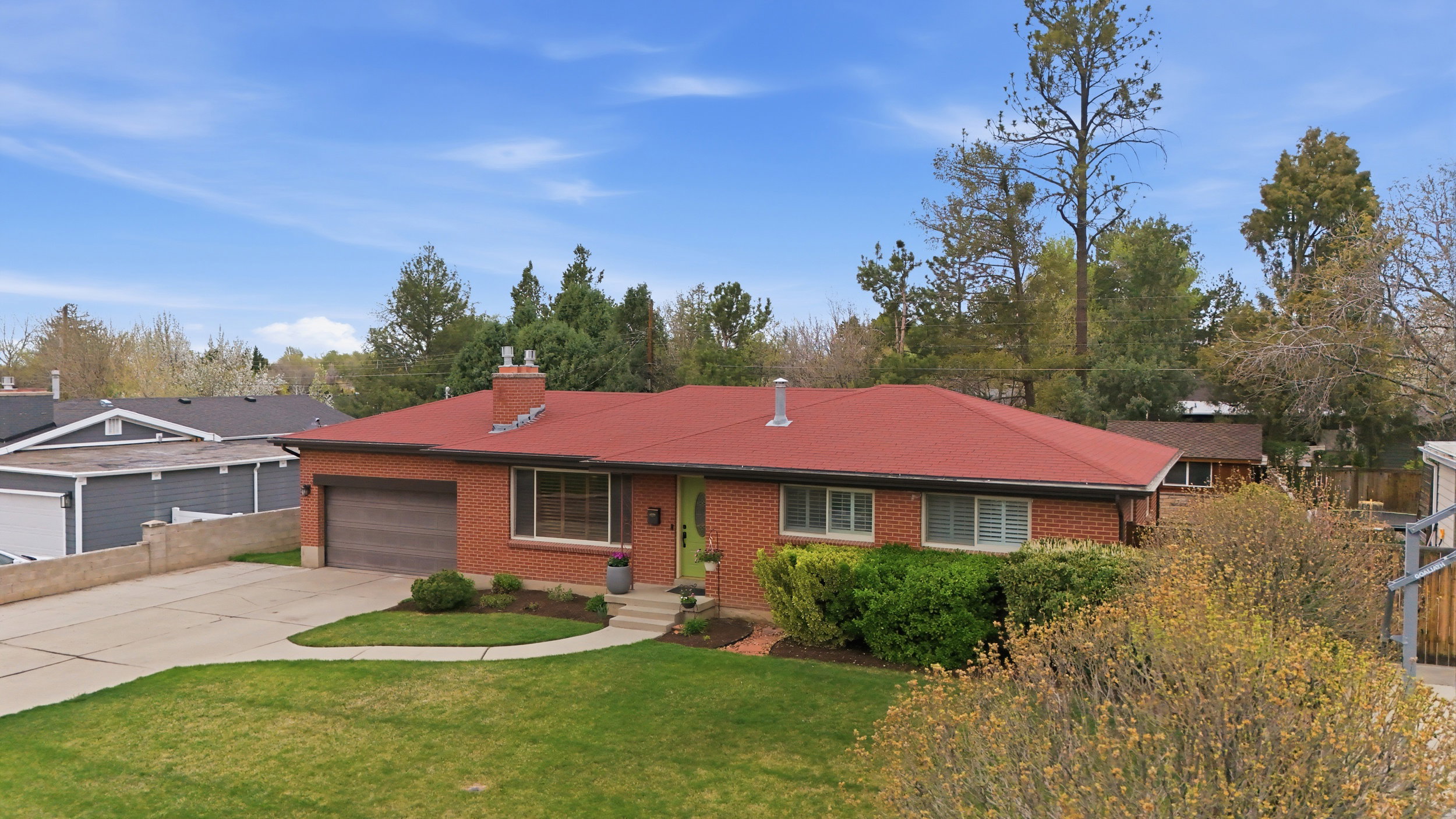 Rambler-style home with concrete driveway, brick siding, a garage, and a chimney
