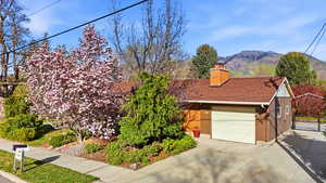 View of front of house with a chimney, an attached garage, a mountain view, roof with shingles, and concrete driveway