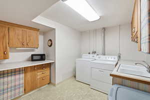 Laundry room featuring cabinet space, light floors, and separate washer and dryer