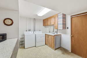 Laundry room featuring light floors, cabinet space, and washer and dryer