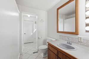 Half bath featuring vanity, light tile patterned floors, and tasteful backsplash