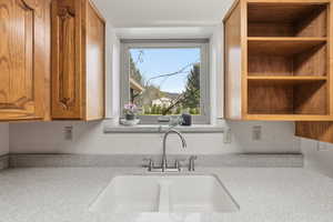 Kitchen featuring light stone counters, wood finish cabinets, and open shelves