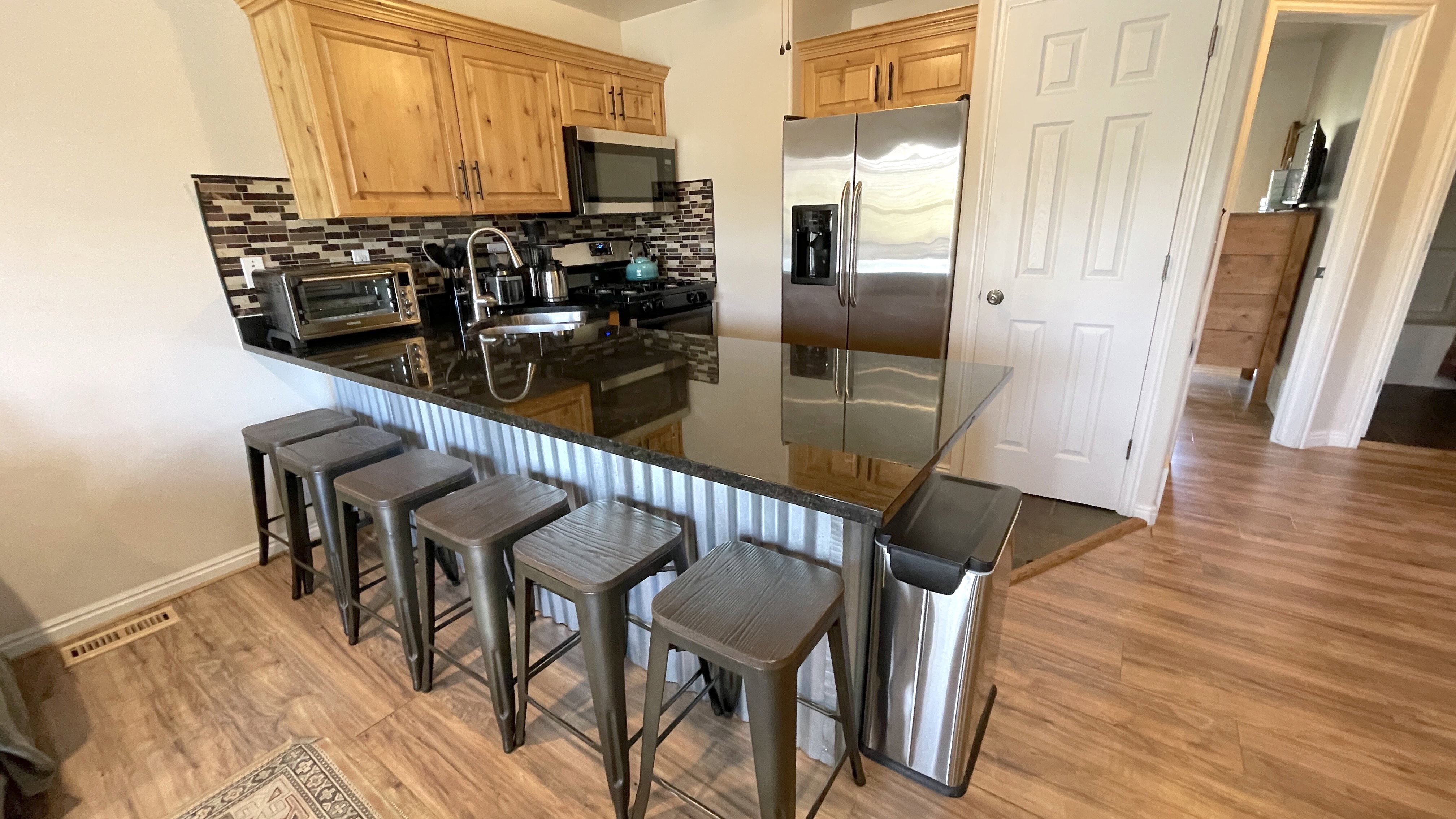 Kitchen featuring a kitchen bar, a peninsula, stainless steel appliances, dark stone counters, and light wood-style floors