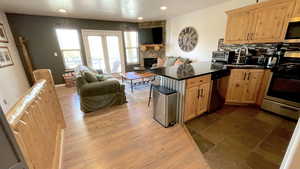 Kitchen featuring open floor plan, a peninsula, stainless steel appliances, light wood finish cabinets, and decorative backsplash