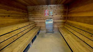Sauna featuring wooden walls, wooden ceiling, and unfinished concrete flooring