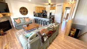 Living area with light wood-style flooring, a ceiling fan, and a fireplace