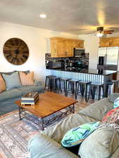 Living room with light wood-style flooring, a textured ceiling, and ceiling fan
