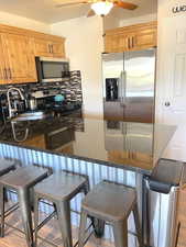 Kitchen with stainless steel appliances, a breakfast bar, and dark stone countertops