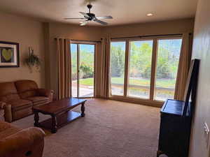 Carpeted living area featuring a ceiling fan and recessed lighting