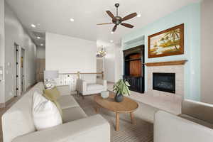 Living room with suspended lighting, a tile fireplace, a ceiling fan, and carpet flooring