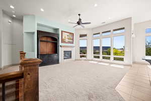 Living room with light carpet, ceiling fan, a tile fireplace, recessed lighting, and light tile patterned flooring