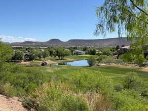 View of mountain background featuring a nearby body of water and a golf course
