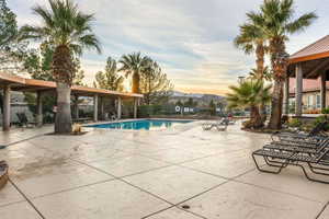 Pool at dusk featuring a patio and a community pool