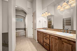 Full bath featuring double vanity, light tile patterned floors, and a garden tub