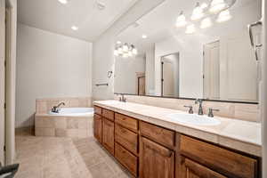 Bathroom featuring double vanity, a garden tub, light tile patterned floors, and recessed lighting