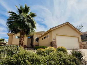 View of front of property with a garage, stucco siding, driveway, and stone siding