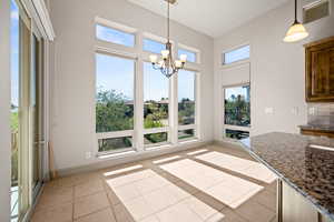 Unfurnished dining area featuring hanging lights, a high ceiling, and light tile patterned floors