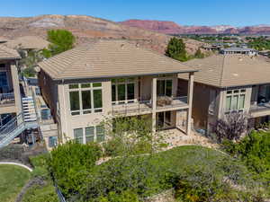 Rear view of property with stucco siding, a balcony, a mountain view, a tile roof, and a patio