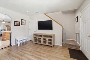 Living room with ceiling fan, light wood-type flooring, and arched walkways