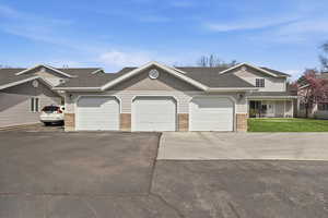 View of front of house with brick siding, roof with shingles, driveway, and a front lawn