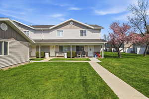 Traditional home featuring covered porch, a front lawn, and a shingled roof