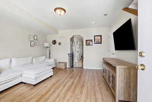 Living room featuring arched walkways and light wood finished floors