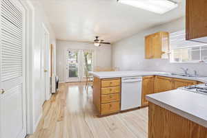 Kitchen with a peninsula, light countertops, light wood-style flooring, white appliances, and ceiling fan