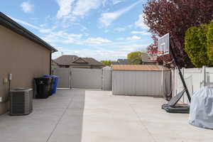 Fenced backyard with a gate, area for grilling, a storage unit, and a patio area
