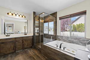 Full bathroom featuring double vanity, a stall shower, a tub with jets, and dark wood-style flooring