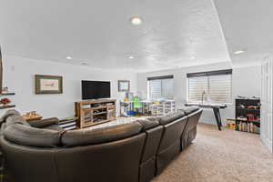 Living area featuring a textured ceiling, light carpet, and recessed lighting