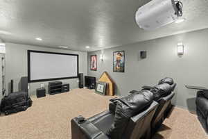 Cinema room with a textured ceiling, light colored carpet, and recessed lighting