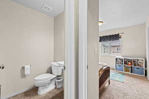 Ensuite bathroom with toilet and light carpet