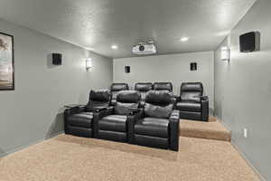 Carpeted cinema room featuring baseboards and a textured ceiling