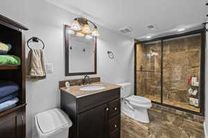 Full bathroom with vanity, a shower stall, recessed lighting, a textured ceiling, and dark stone finish floors