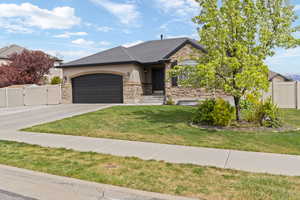 View of front of house featuring a gate, a garage, concrete driveway, stone siding, and stucco siding