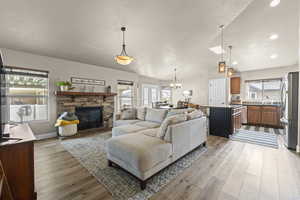 Living area featuring light wood-type flooring, a stone fireplace, and hanging lights