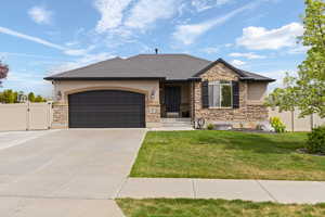 View of front facade featuring a gate, a garage, driveway, and stucco siding