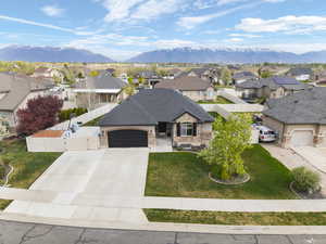 View of front of home with a gate, an attached garage, a residential view, stone siding, and driveway